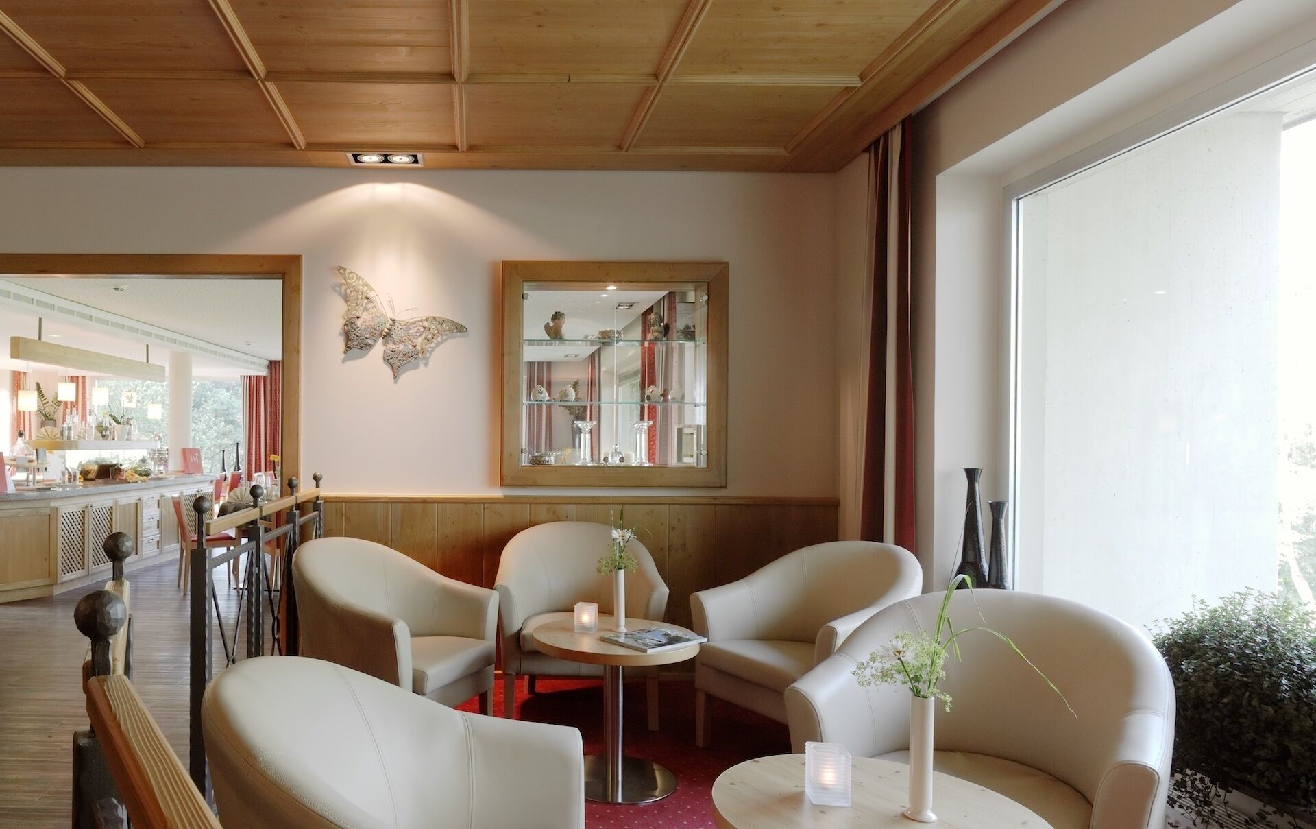A modern interior with a wooden ceiling, a large mirror, and a seating area with two chairs and a table.