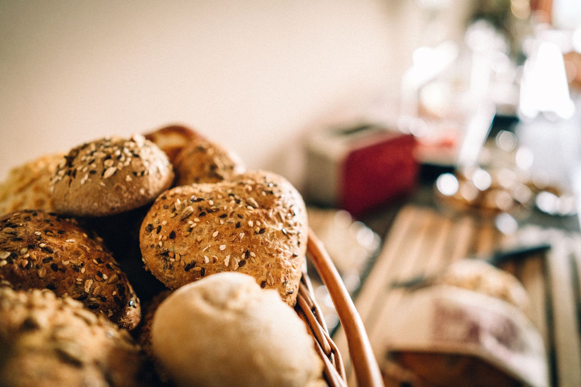 A basket of various breads and pastries, including whole grain and seeded varieties.