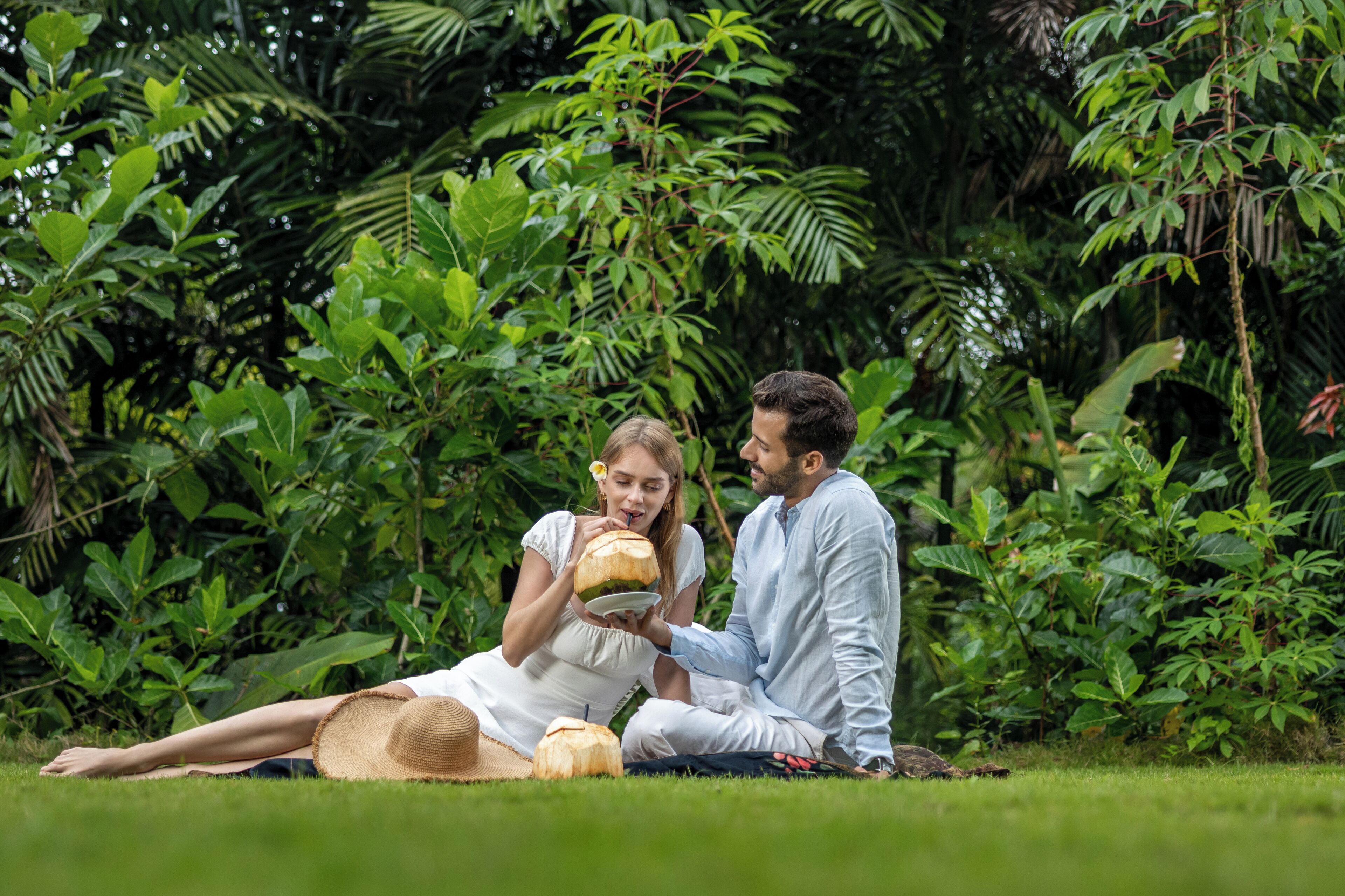 Una pareja sentada sobre la hierba, rodeada de abundante vegetación.