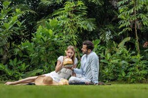 Una pareja sentada sobre la hierba, rodeada de abundante vegetación.