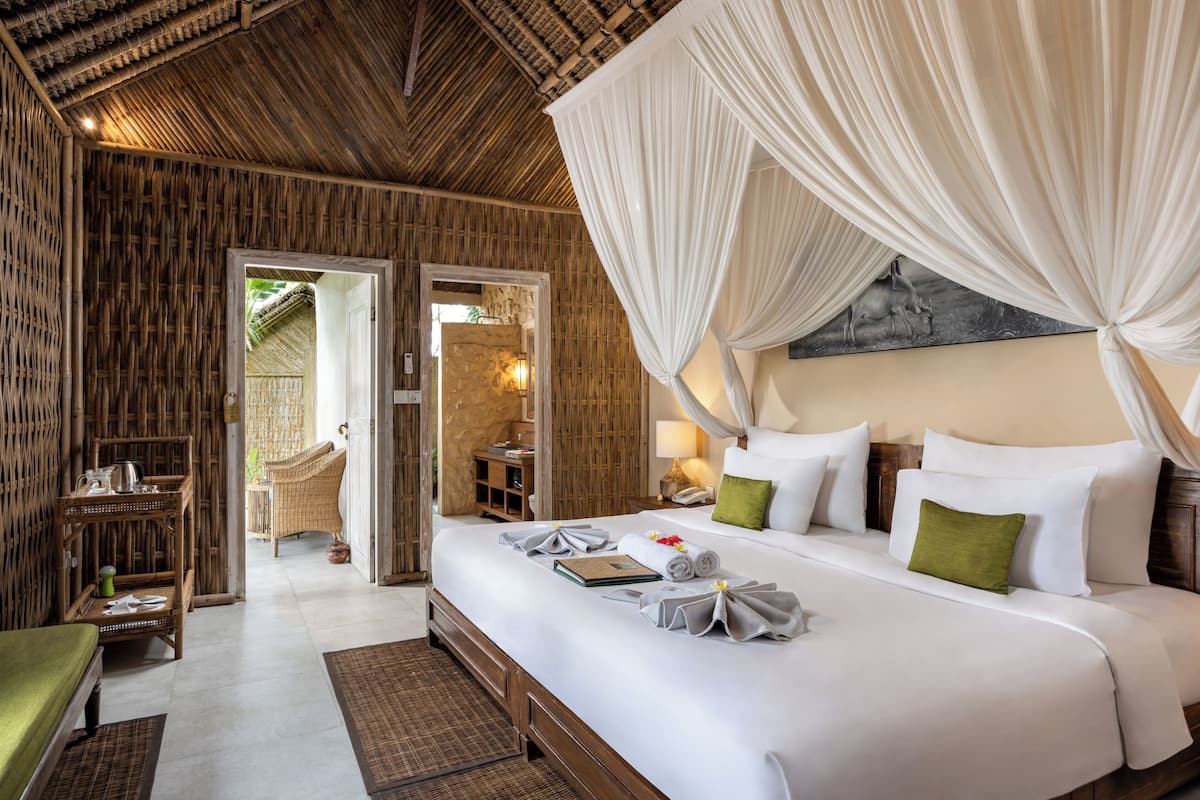Ein geräumiges Schlafzimmer mit einem großen Bett, einer Holzbalkendecke und Blick ins Freie.