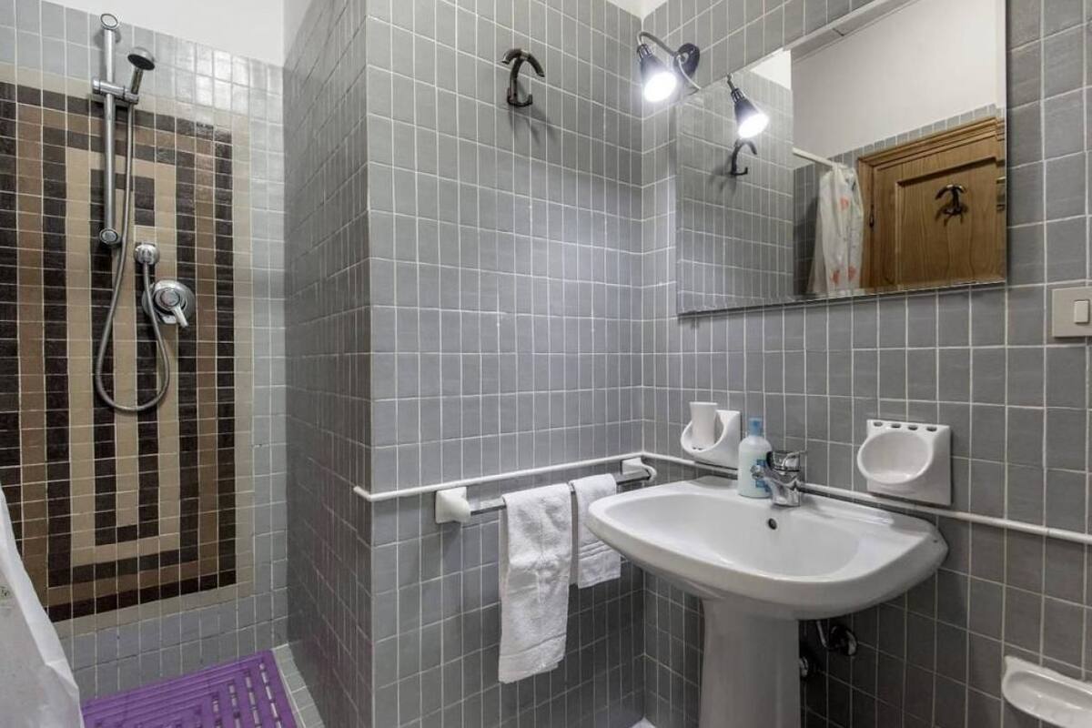 A bathroom with a shower, a sink, and a mirror.