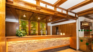 A reception area with a stone wall, wooden ceiling beams, and a red rug. - Flair Hotel Werbetal (Waldeck)
