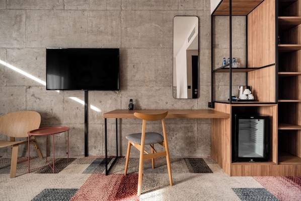 Una habitación moderna con un escritorio de madera, televisor, silla y estantería empotrada.
