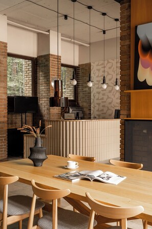 Un comedor moderno con una mesa de madera, sillas y un jarrón con plantas secas.