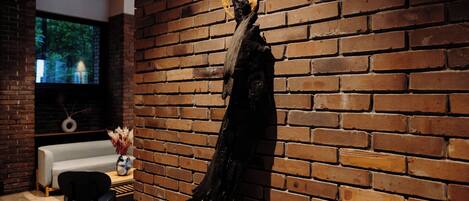 A statue on a pedestal against a brick wall, a sofa, and a television in a room.