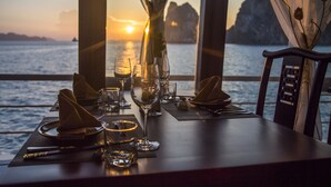 Une table dressée pour le dîner, avec vue sur le coucher de soleil sur l’eau.