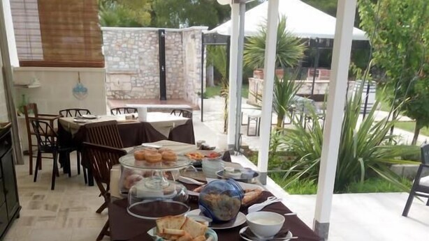 Un área de comedor cubierta con diversas opciones de comida sobre una larga mesa, incluyendo pizzas, pan y una tabla de quesos.