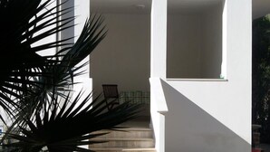 Un edificio blanco con una escalera que lleva a un área techada.
