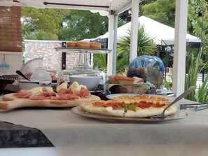 Una mesa de buffet con diversos alimentos, como pizza, queso y carnes.