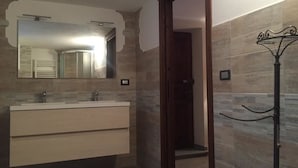 A bathroom with a modern vanity, a large mirror, and a shower area.