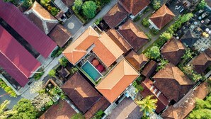 Vista aérea de un área residencial con varias casas, una piscina central y abundante vegetación.