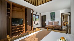 Un dormitorio amplio con una cama grande, televisión, sofá y zona de comedor.
