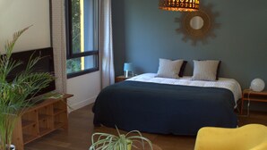 A bedroom with a bed, bedside table, lamp, and a potted plant. - Effet Lodge (Saint-Cyr-au-Mont-d'Or)