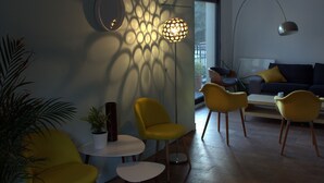 A modern living room with yellow chairs, a round table, a floor lamp, and a sofa with cushions. - Effet Lodge (Saint-Cyr-au-Mont-d'Or)