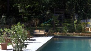A pool area with wooden lounge chairs, a small bridge, and potted plants. - Effet Lodge (Saint-Cyr-au-Mont-d'Or)