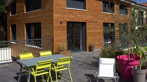 A modern two-story building with a wooden facade, large windows, and a balcony with outdoor seating. - Effet Lodge (Saint-Cyr-au-Mont-d'Or)