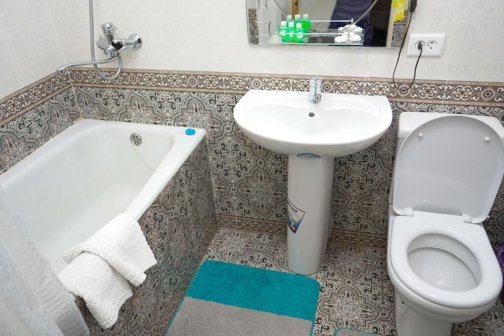 A bathroom with a bathtub, sink, and toilet, all with patterned tile walls.