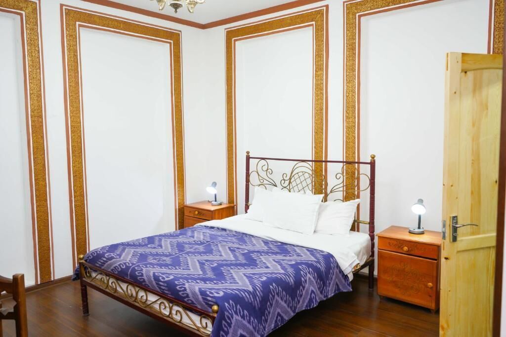 A bedroom with a bed, two bedside tables, and a wooden door.