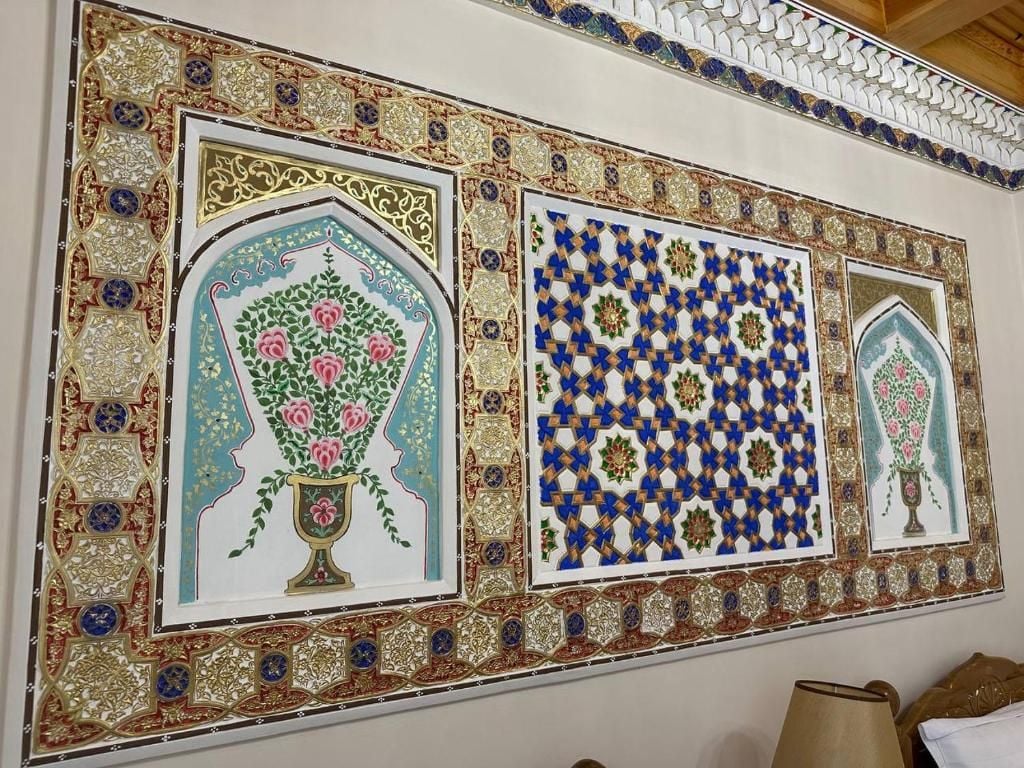 Un mur orné de motifs complexes en mosaïque, comprenant des motifs floraux et géométriques.