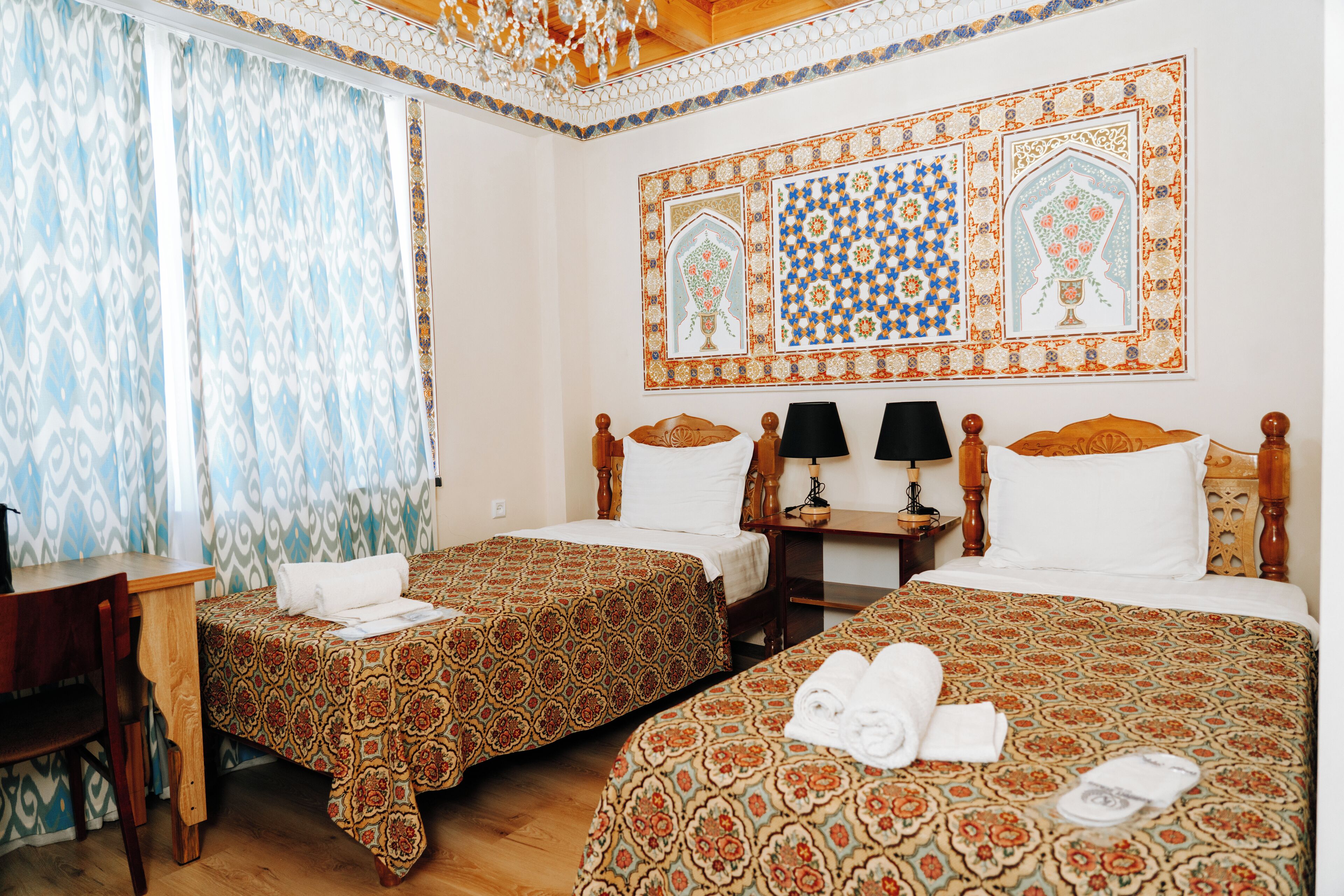 A hotel room with two beds, a desk, and a chair.
