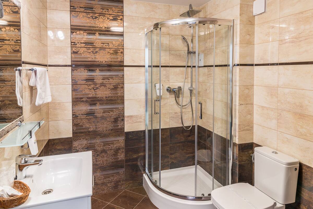 A modern bathroom with a glass-enclosed shower, a white sink, and a toilet.