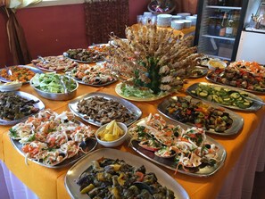 Una mesa de buffet con diversos platos, entre ellos mariscos, ensaladas y verduras.