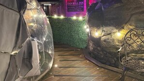 A nighttime view of a hotel entrance with a sign for 'Tan Hill Inn' and a decorative wall with lights. - The World Famous Tan Hill Inn (Richmond)