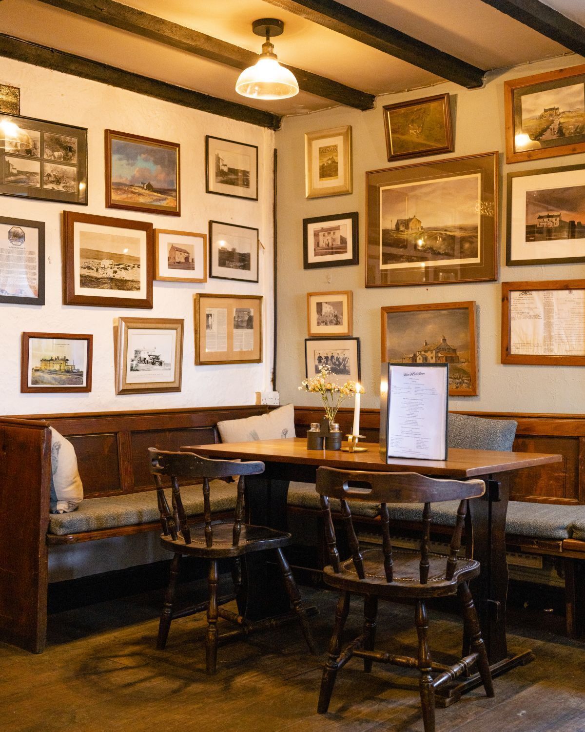 A cozy dining area with wooden furniture, a table with a menu, and walls adorned with framed photographs.