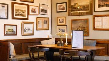 A cozy dining area with wooden furniture, a table with a menu, and walls adorned with framed photographs.