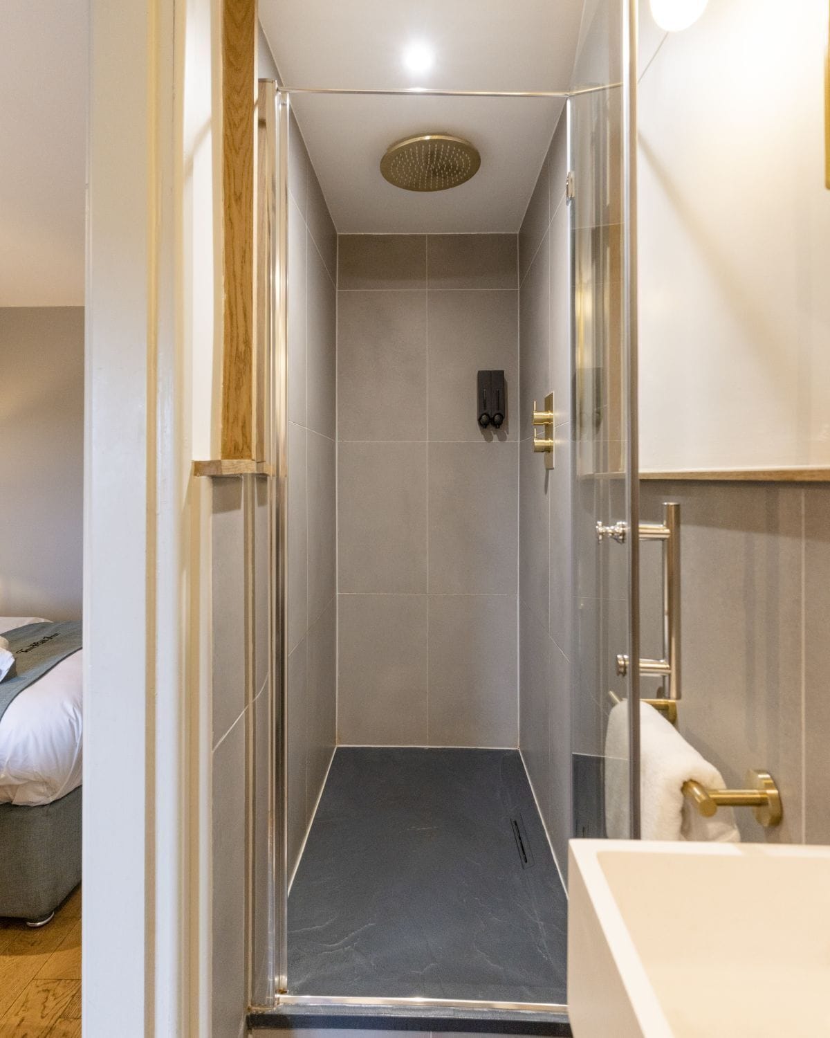 Een moderne douche met een glazen deur, een handdoekhouder en een douchekop.