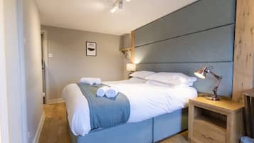 Un dormitorio moderno con una cama grande, una lámpara de noche y una mesita de madera.
