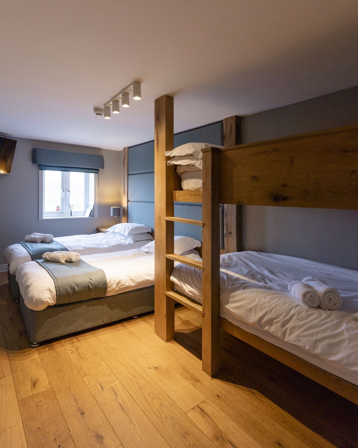 Una habitación con dos literas, un ventanal con vistas y suelo de madera.