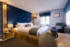 A modern hotel room with a large bed, a wooden headboard, a chair, and a small table. - The World Famous Tan Hill Inn (Richmond)