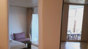 A modern hotel room with a bed, a small seating area, and a view of the outside balcony. - Klidon Dreamy Living Suites (Mykonos)