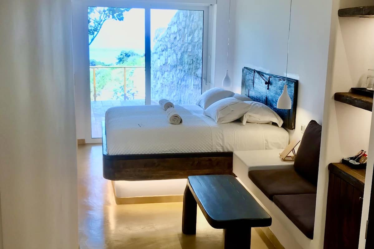 Un dormitorio con cama, banco y vistas al exterior.
