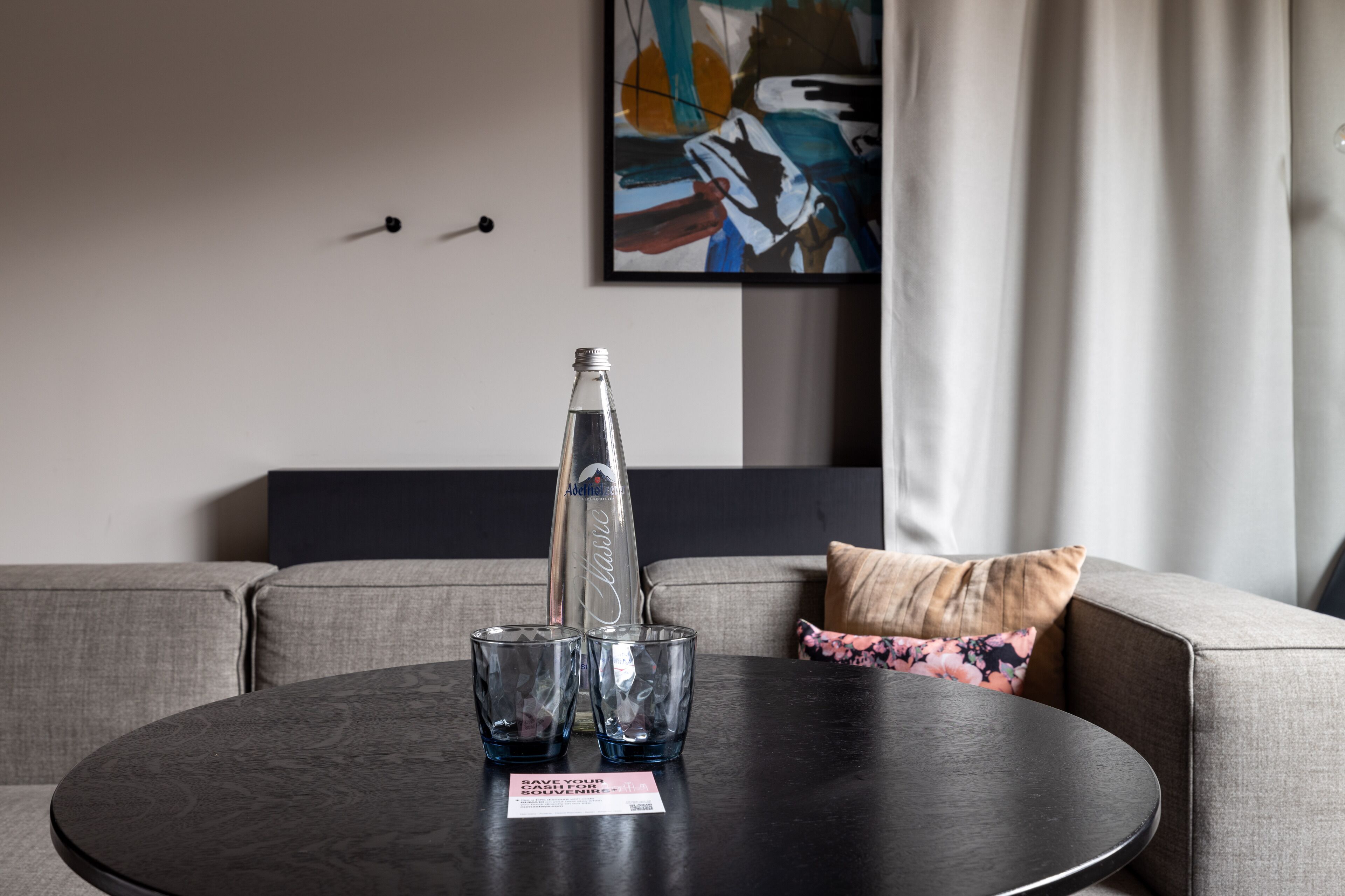 Ein modernes Wohnzimmer mit einem runden Tisch, zwei Gläsern und einer Wasserflasche.