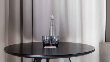 A round table with a bottle and two glasses on it, set against a curtain backdrop.