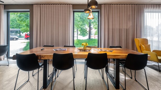 A dining area with a wooden table, black chairs, and a yellow chair.