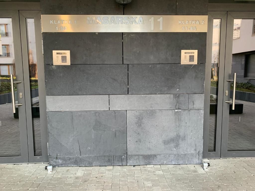 Une entrée moderne, caractérisée par une grande façade en pierre sombre.