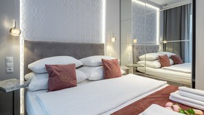 Una habitación de hotel moderna con una cama grande, una mesita de noche, un espejo y una pared con un diseño geométrico.