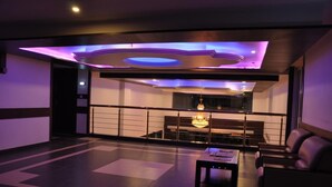 A modern interior with a seating area, a chandelier, and a view of a cityscape through a glass partition.