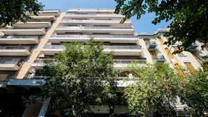Un edificio residencial de varios pisos con balcones y un árbol en primer plano.