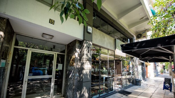 Entrada de un edificio con puerta de vidrio, un letrero con el número 15 y un área exterior cubierta con un cartel.