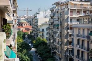 A multi-story residential building with balconies, a narrow street, and construction cranes in the background. - Art Maison (Thessaloniki)