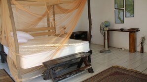 A room with a four-poster bed, a wooden nightstand, a globe, and framed maps on the wall.