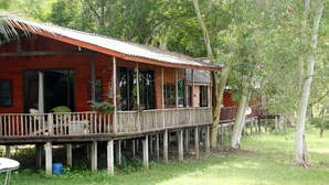 A wooden house with a balcony, surrounded by trees.