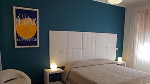 Une chambre à coucher comprenant un lit, des tables de chevet, une chaise et une œuvre d’art murale.