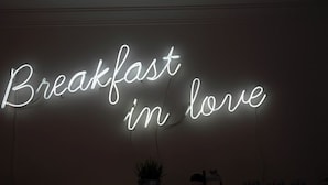 Une enseigne au néon sur un mur, avec l’inscription « Petit-déjeuner en amoureux ».