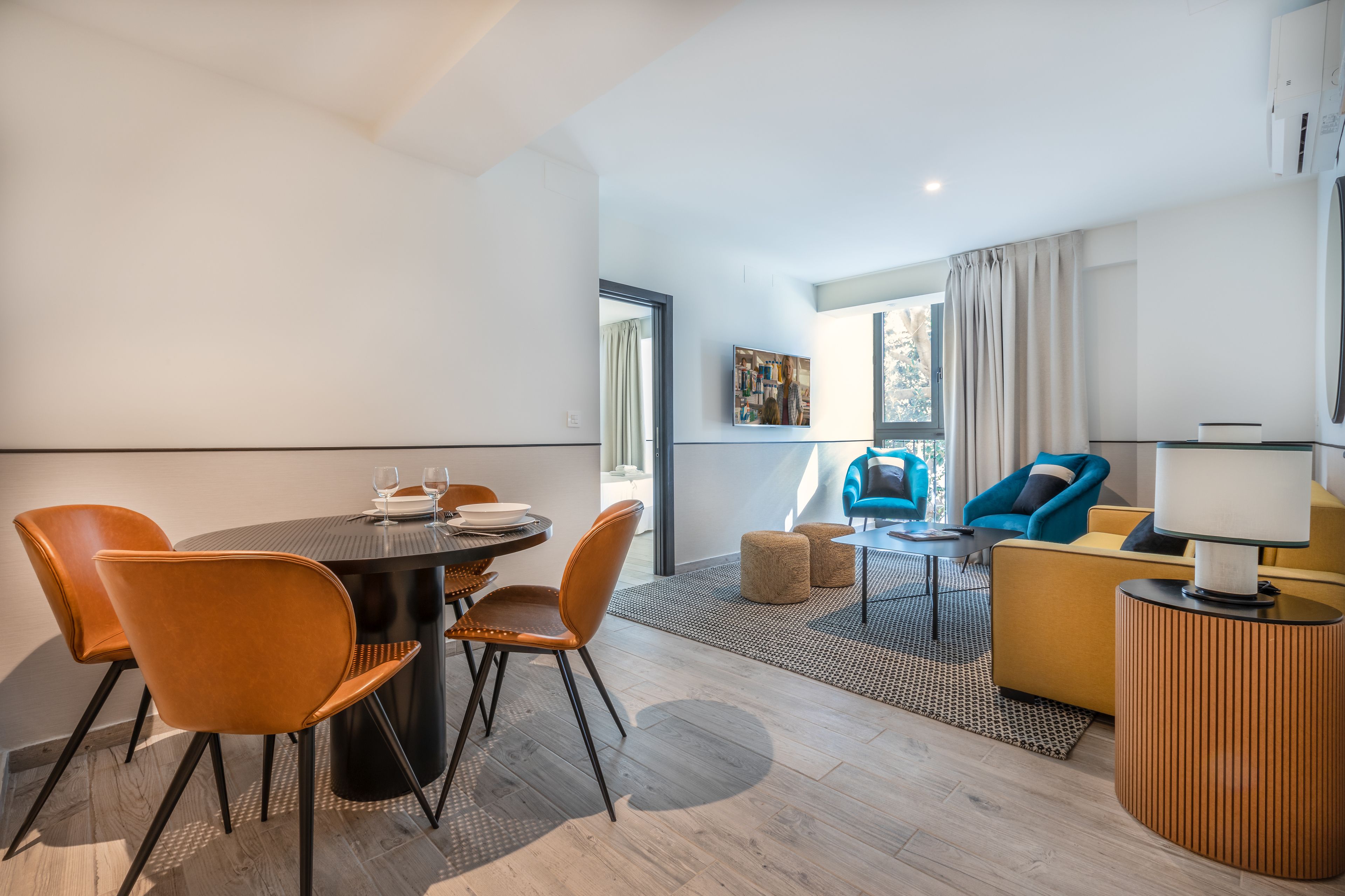 Ein modernes Wohnzimmer mit Essbereich, ausgestattet mit einem runden Tisch, Stühlen, einer Couch und einer Lampe.